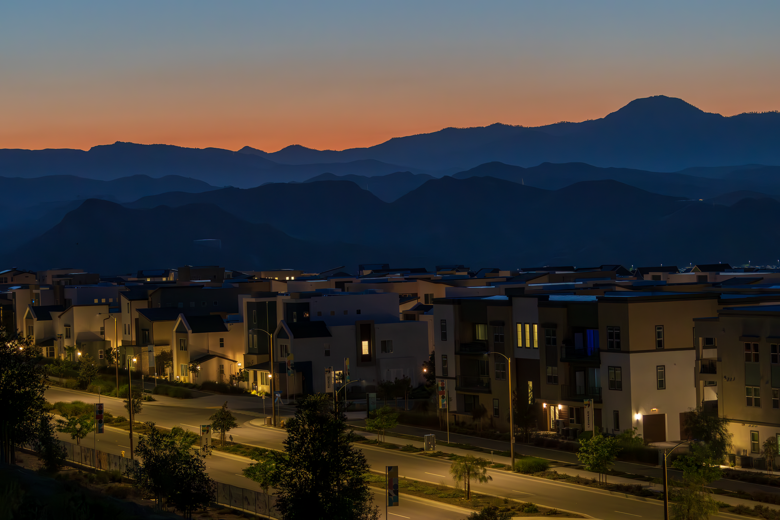 A quiet suburban neighborhood illuminated at dusk with mountains in the background.