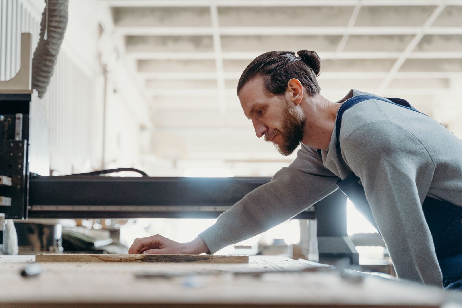 Artisan focuses intently on a woodworking task in a modern, well-lit workshop.