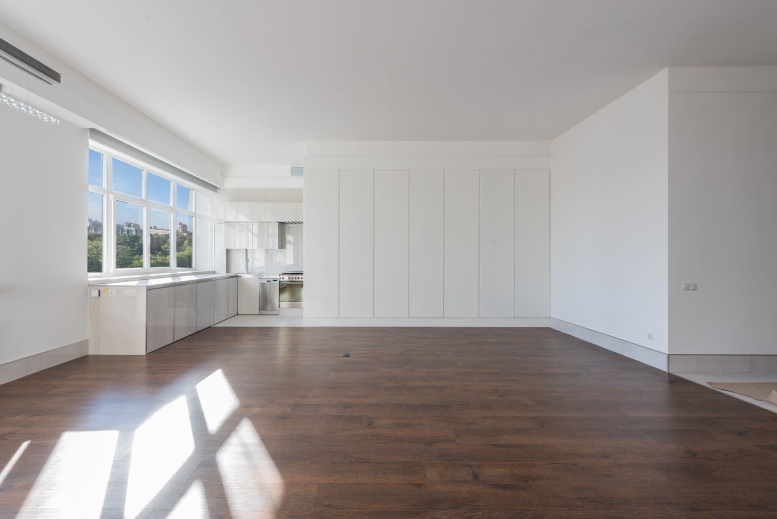 Bright and spacious modern kitchen interior featuring wooden floors and white cabinetry.